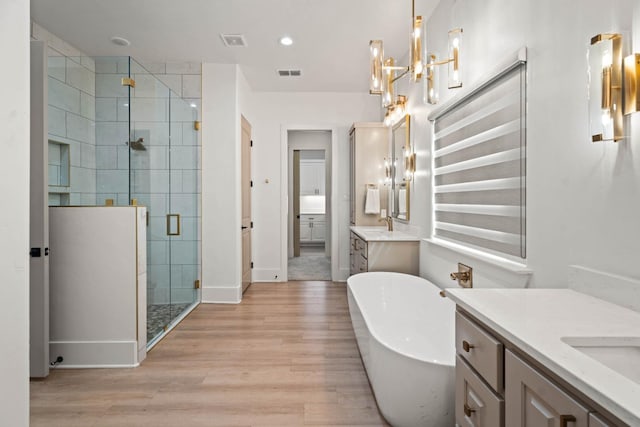 bathroom with independent shower and bath, vanity, and wood-type flooring