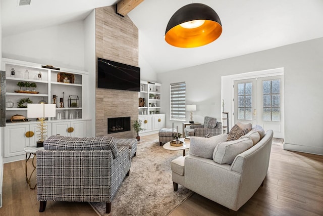 living room featuring high vaulted ceiling, beamed ceiling, wood-type flooring, a tiled fireplace, and french doors