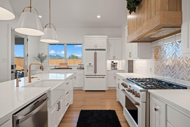 kitchen with high quality appliances, custom exhaust hood, white cabinetry, and decorative light fixtures