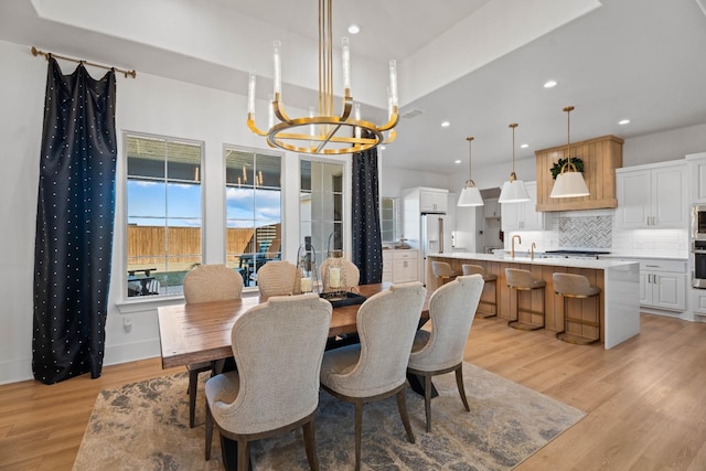 dining area featuring an inviting chandelier, sink, and light wood-type flooring