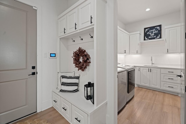 mudroom featuring separate washer and dryer, sink, and light hardwood / wood-style floors