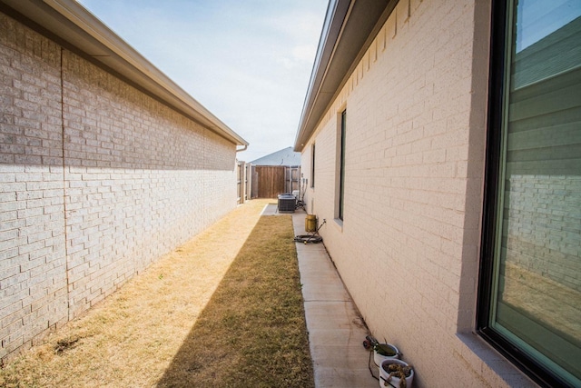 view of home's exterior with brick siding, fence, and central AC unit