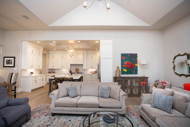 living room with visible vents, lofted ceiling, light wood-style flooring, an inviting chandelier, and recessed lighting