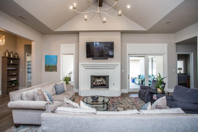 living room with high vaulted ceiling, a brick fireplace, a chandelier, and wood finished floors