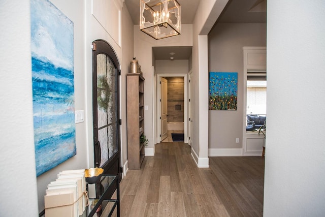 entrance foyer with a notable chandelier, baseboards, and wood finished floors