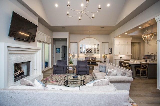 living room with a chandelier, high vaulted ceiling, recessed lighting, a fireplace, and dark wood finished floors