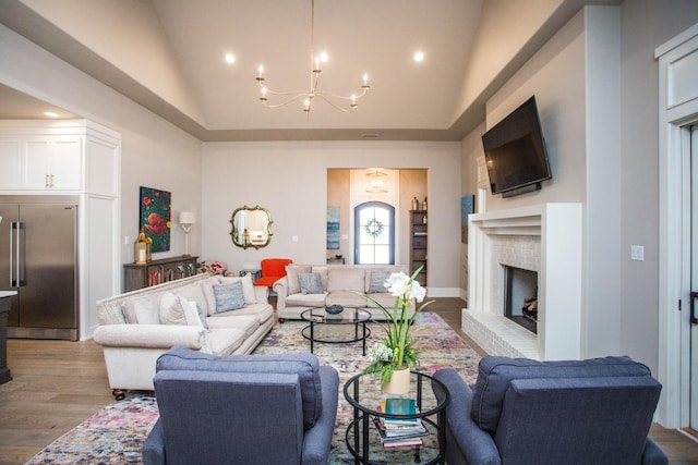 living room featuring a notable chandelier, recessed lighting, light wood-style floors, a brick fireplace, and high vaulted ceiling