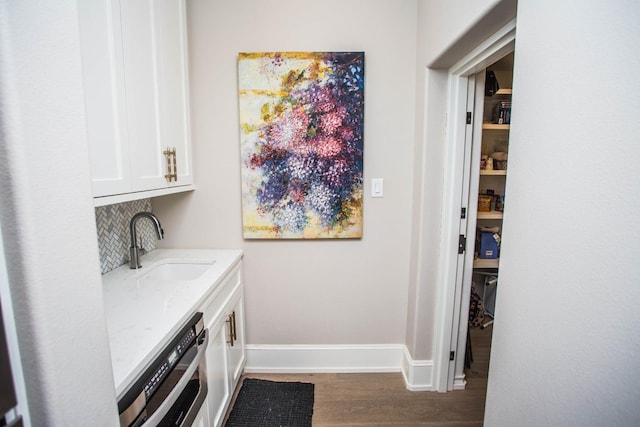 laundry room featuring a sink, baseboards, and dark wood-type flooring