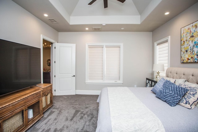 carpeted bedroom with visible vents, a raised ceiling, and recessed lighting