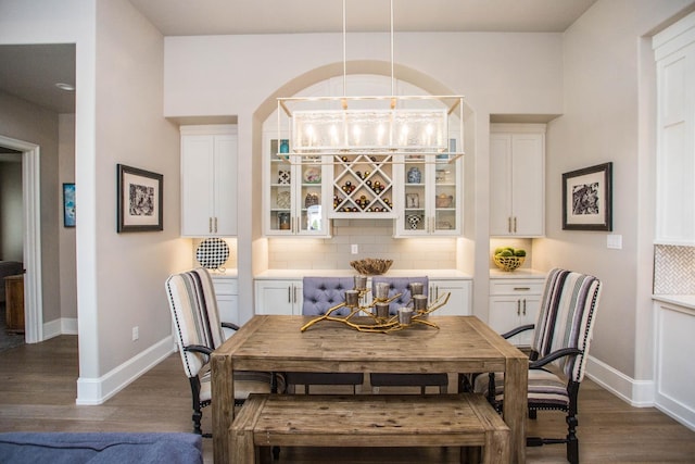 dining area featuring dark wood finished floors, a bar, and baseboards