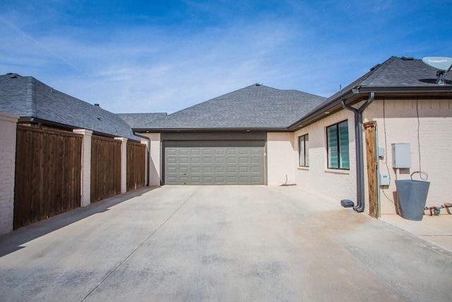 view of home's exterior featuring brick siding, a shingled roof, an attached garage, fence, and driveway