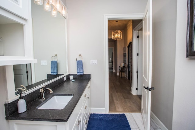 bathroom with an inviting chandelier, baseboards, wood finished floors, and vanity