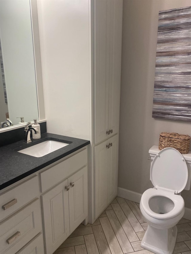 bathroom with toilet, baseboards, and vanity