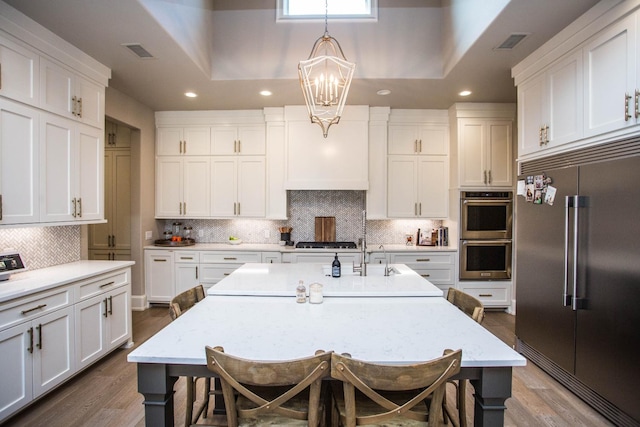 kitchen with hanging light fixtures, visible vents, a center island with sink, and appliances with stainless steel finishes