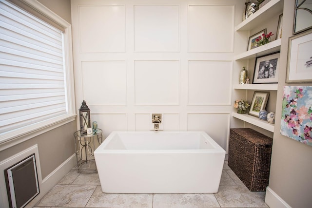 bathroom featuring built in shelves, a soaking tub, and baseboards