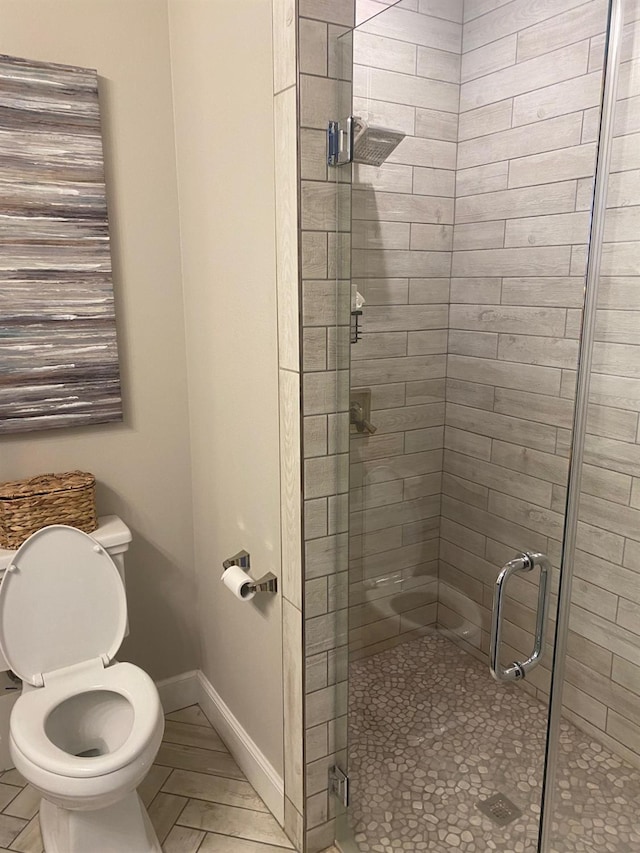 bathroom featuring a stall shower, toilet, and baseboards