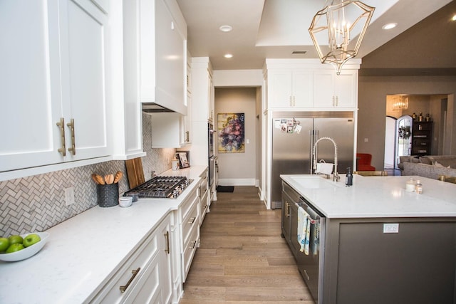 kitchen featuring white cabinetry, stainless steel appliances, and decorative light fixtures