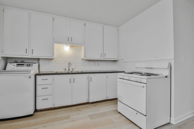 kitchen with washer / dryer, white range with gas cooktop, sink, and white cabinets