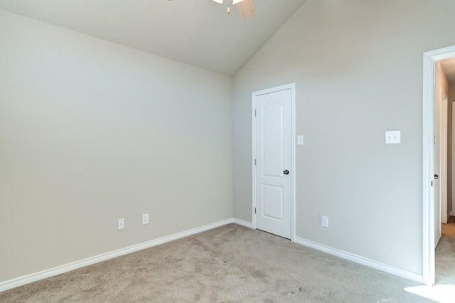 empty room with ceiling fan, vaulted ceiling, and light carpet