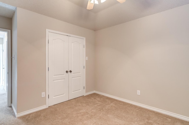 unfurnished bedroom with light carpet, a closet, and ceiling fan