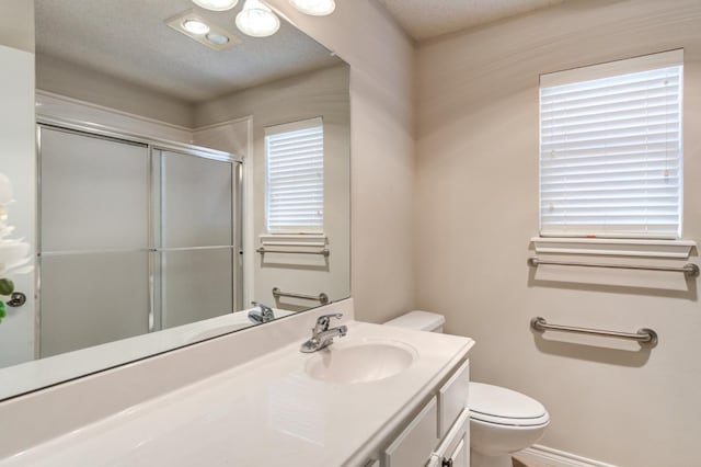 bathroom featuring vanity, an enclosed shower, a textured ceiling, and toilet