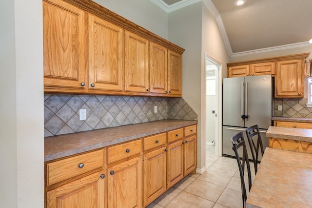 kitchen with light tile patterned floors, crown molding, high quality fridge, and decorative backsplash