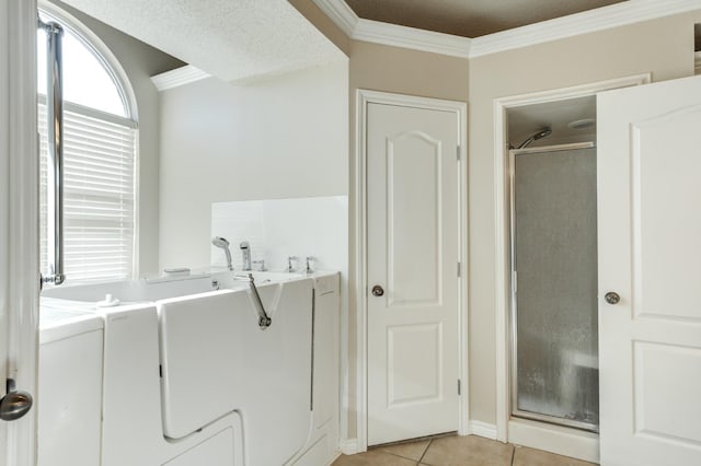 bathroom with tile patterned flooring, plus walk in shower, separate washer and dryer, and ornamental molding