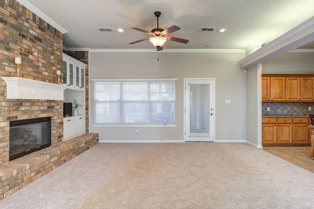 unfurnished living room featuring ornamental molding, light colored carpet, a textured ceiling, and a fireplace