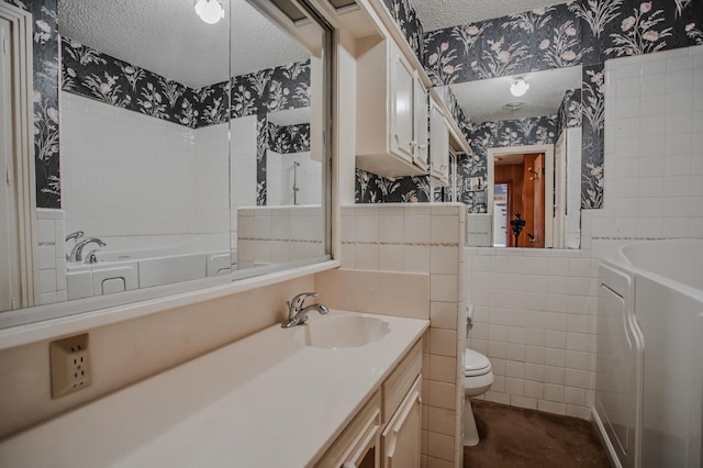 bathroom featuring vanity, a bath, a textured ceiling, and toilet