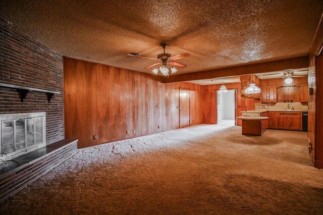 unfurnished living room featuring light colored carpet, a textured ceiling, wooden walls, ceiling fan, and a fireplace
