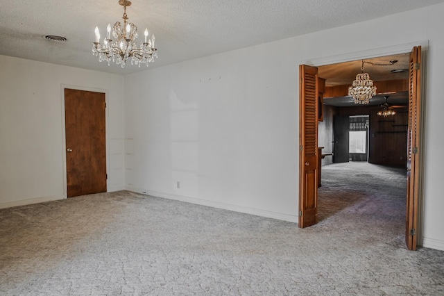spare room with a notable chandelier, a textured ceiling, and carpet
