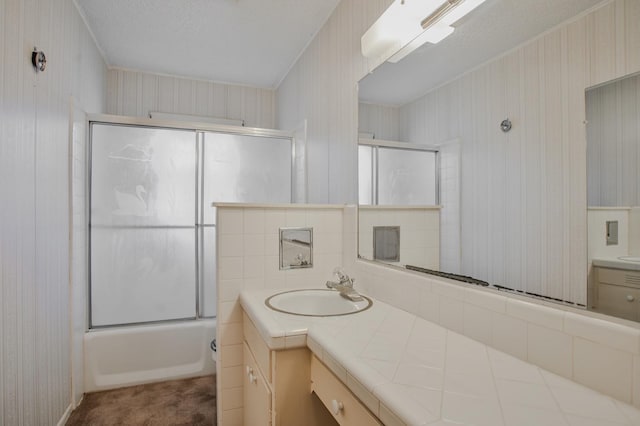 bathroom with vanity, combined bath / shower with glass door, and a textured ceiling