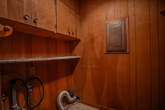 washroom featuring cabinets, washer hookup, electric panel, and wood walls