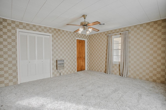 unfurnished bedroom featuring ceiling fan, a closet, and heating unit