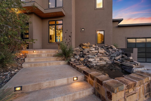 exterior entry at dusk featuring a garage