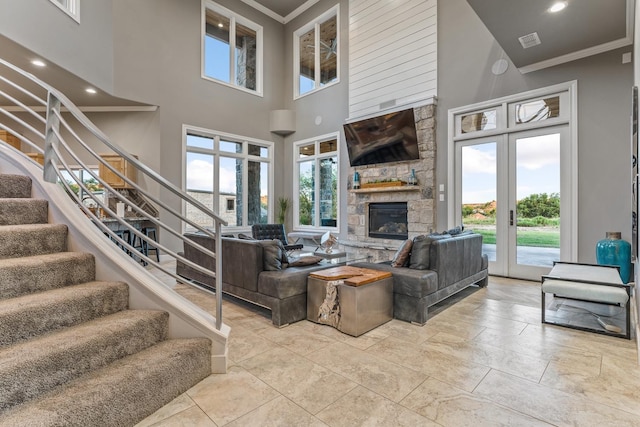 living room featuring french doors, ornamental molding, a fireplace, and a high ceiling