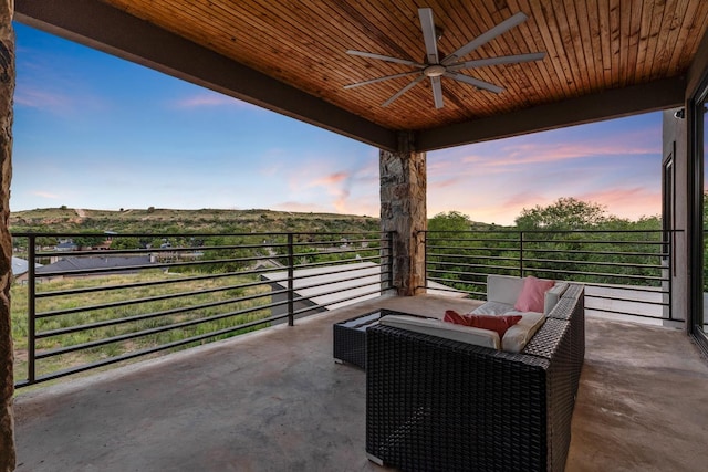 patio terrace at dusk with an outdoor living space, a balcony, and ceiling fan