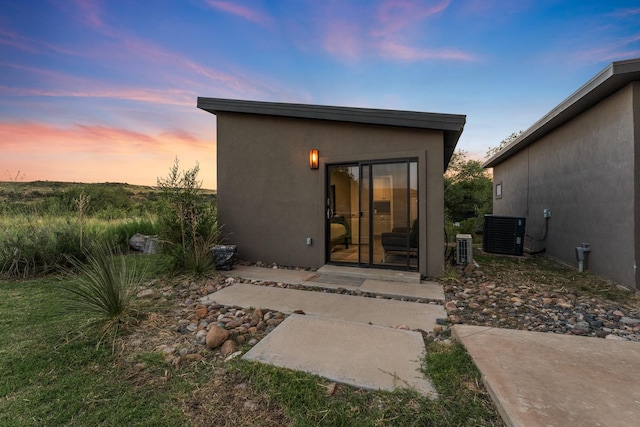 back house at dusk with a patio and cooling unit