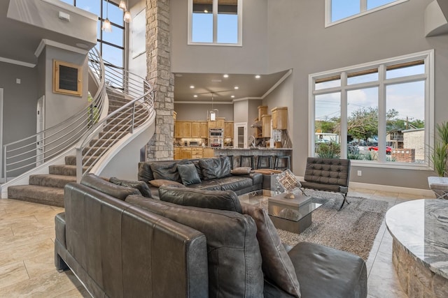 living room with crown molding, a healthy amount of sunlight, and a towering ceiling