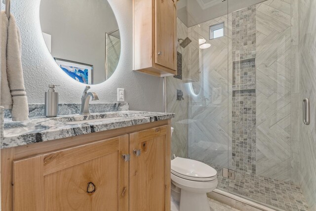 bathroom with vanity, a shower with door, and toilet