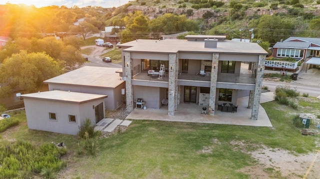 rear view of property featuring a patio area, a balcony, and a lawn