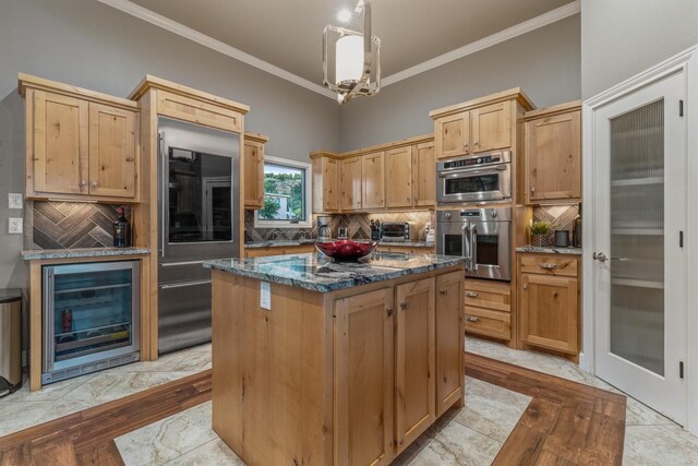 kitchen with decorative light fixtures, a kitchen island, dark stone counters, beverage cooler, and backsplash