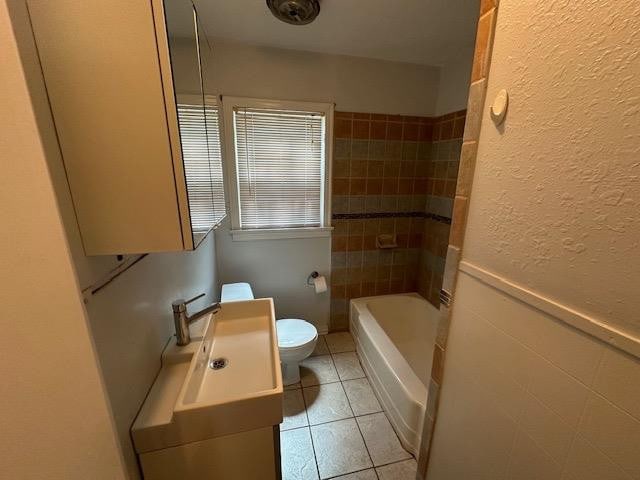 full bathroom featuring tile patterned floors, toilet, tiled shower / bath combo, and vanity