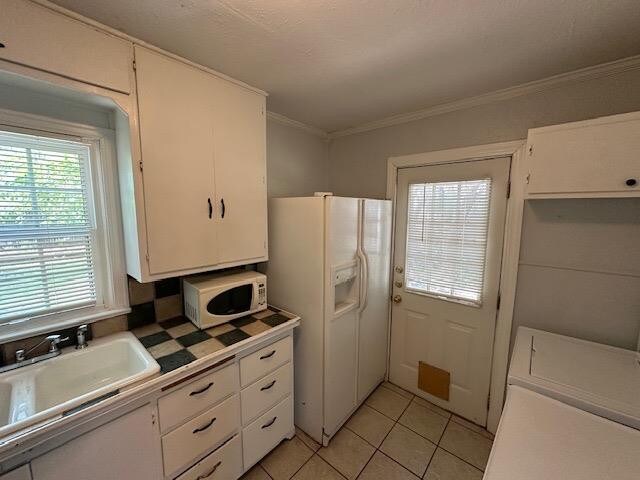 kitchen with sink, white cabinetry, crown molding, light tile patterned floors, and white appliances