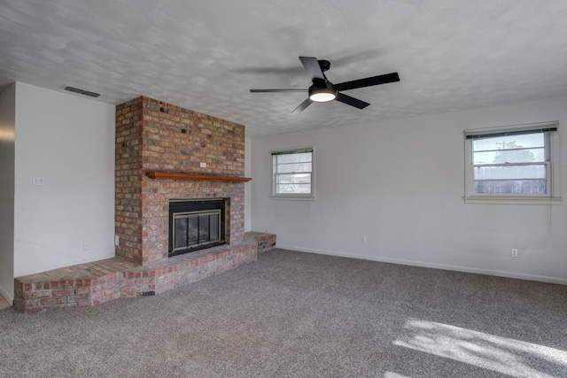 unfurnished living room featuring ceiling fan, a fireplace, a textured ceiling, and carpet