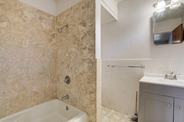 bathroom with tile walls, vanity, and tiled shower / bath combo