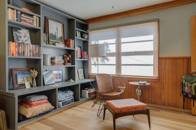 sitting room with hardwood / wood-style flooring, crown molding, and wooden walls