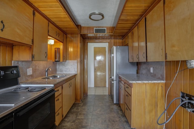 kitchen with black electric range oven, sink, stainless steel refrigerator, dark tile patterned floors, and backsplash