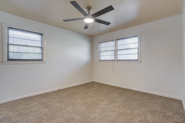 carpeted empty room with ceiling fan and a wealth of natural light