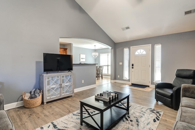 living room featuring high vaulted ceiling, a chandelier, and light hardwood / wood-style floors